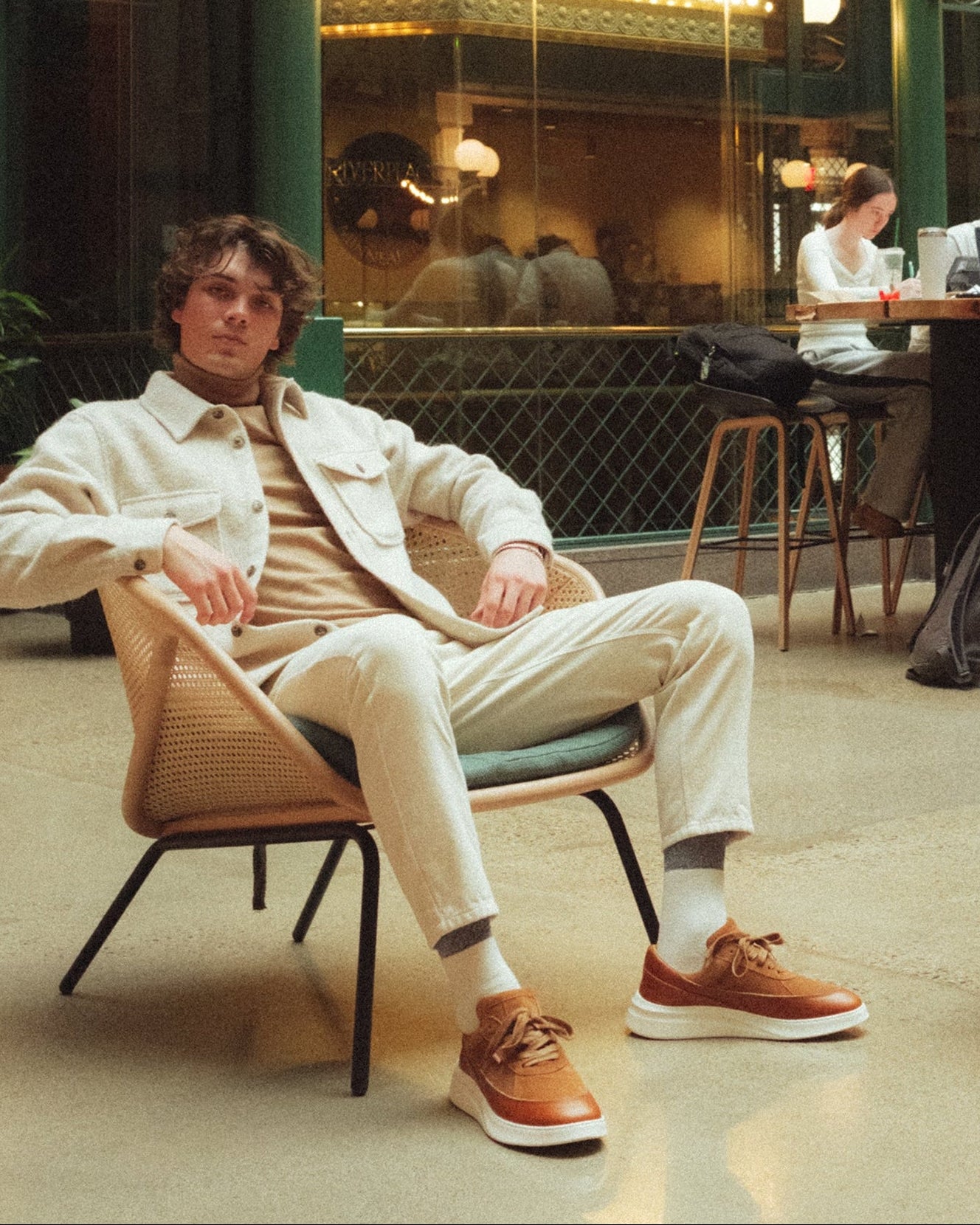 Man sitting in a modern indoor setting with green walls and glass ceiling